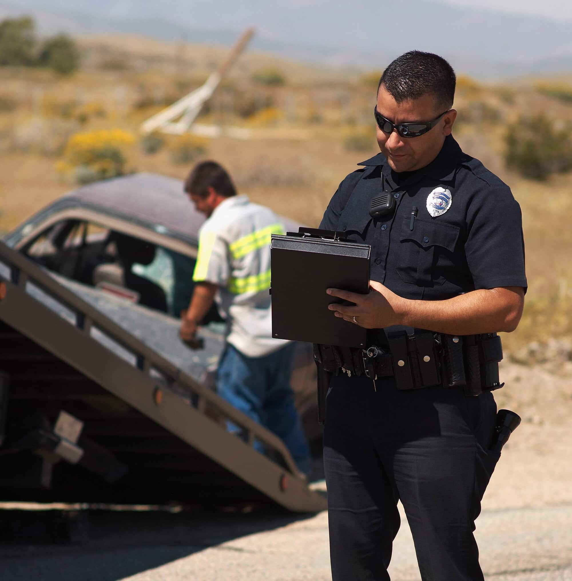 Police officer writing on a clipboard beside a car stopped on the roadside
