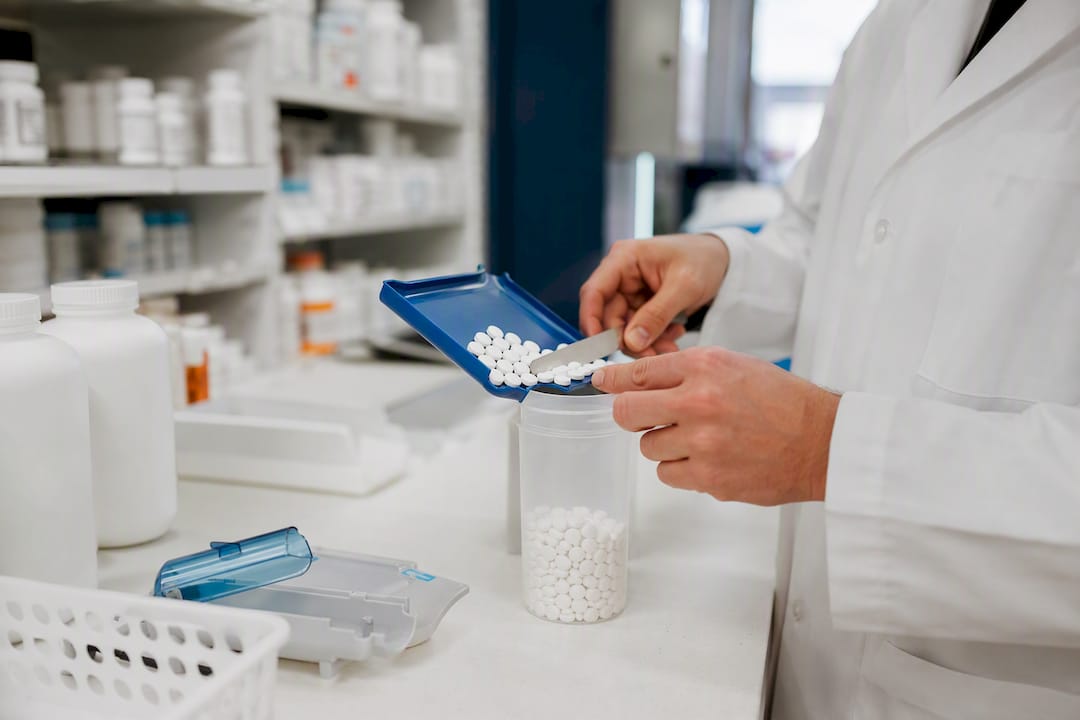 Pharmacist hands counting pills into container