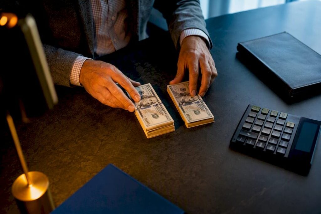 Hands separating settlement funds beside calculator