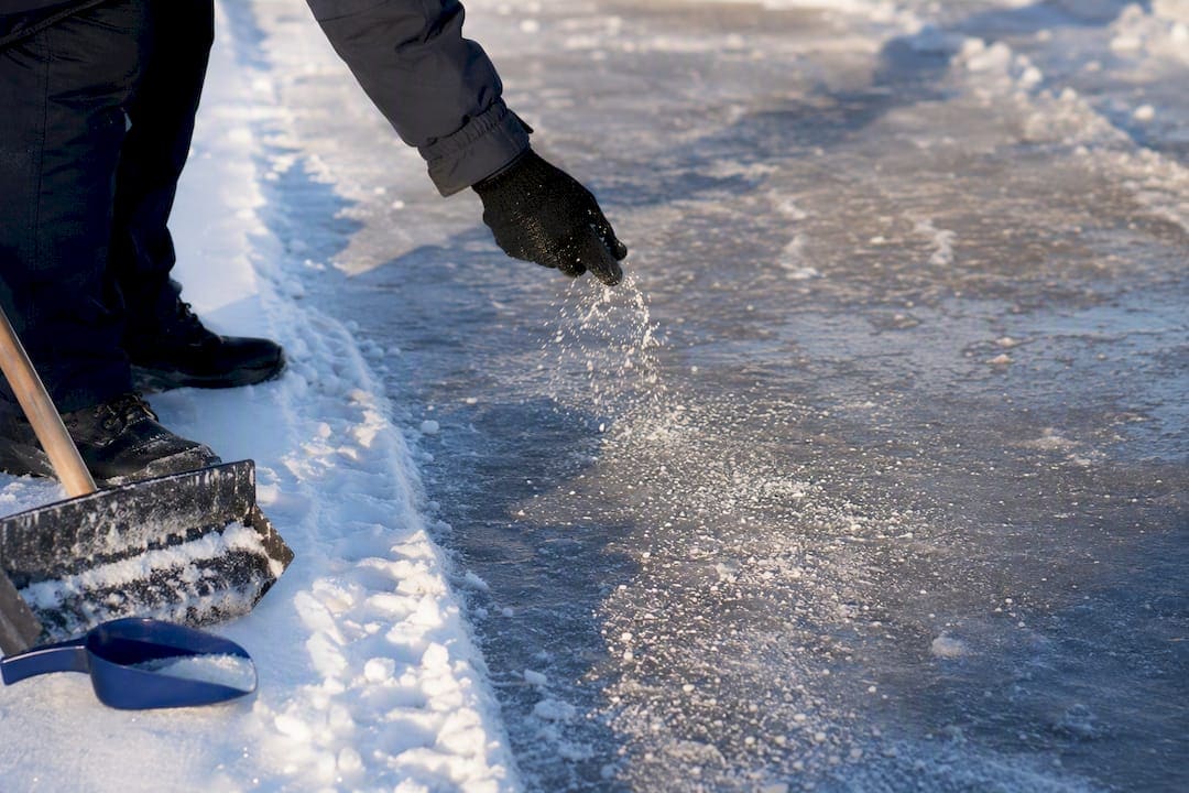 Worker salting an icy parking lot