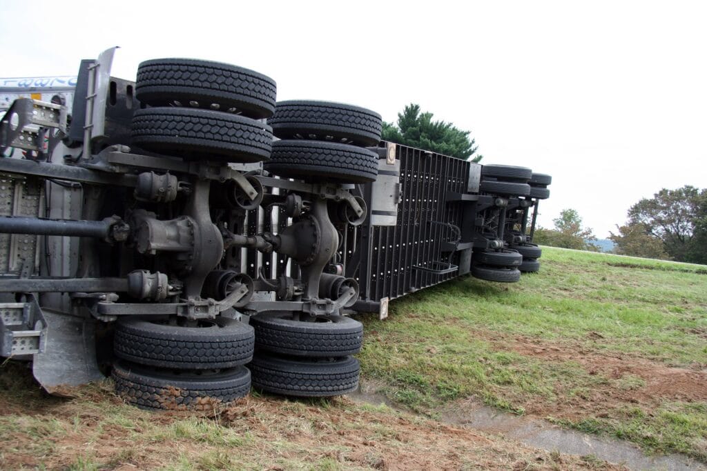 Overturned semi-trailer lying on its side beside a grassy roadside